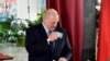 Belarusian President Alexander Lukashenko holds a ballot and a passport before casting his vote at a polling station during the presidential election in Minsk, Belarus, Aug. 9, 2020. 