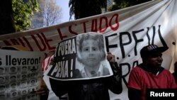 Demonstrator covers face with poster reading "Pena Out" during protest in support of 43 missing students outside office of Mexico's Attorney General, Mexico City, Nov. 27, 2014.