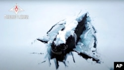 A Russian nuclear submarine breaks through the Arctic ice during military drills at an unspecified location, March 26, 2021, in this handout photo taken from a footage released by Russian Defense Ministry Press Service.