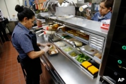 Silvia Ruiz prepares a specialty sandwich at a McDonald's restaurant in Chicago, June 1, 2017. McDonald’s is still trying to shake its image for serving junk food and has made a high-profile pledge to offer healthier options.