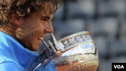 Petenis peringkat kedua dunia, Rafael Nadal, bereaksi saat menggenggam piala turnamen Perancis Terbuka, bulan Juni silam.