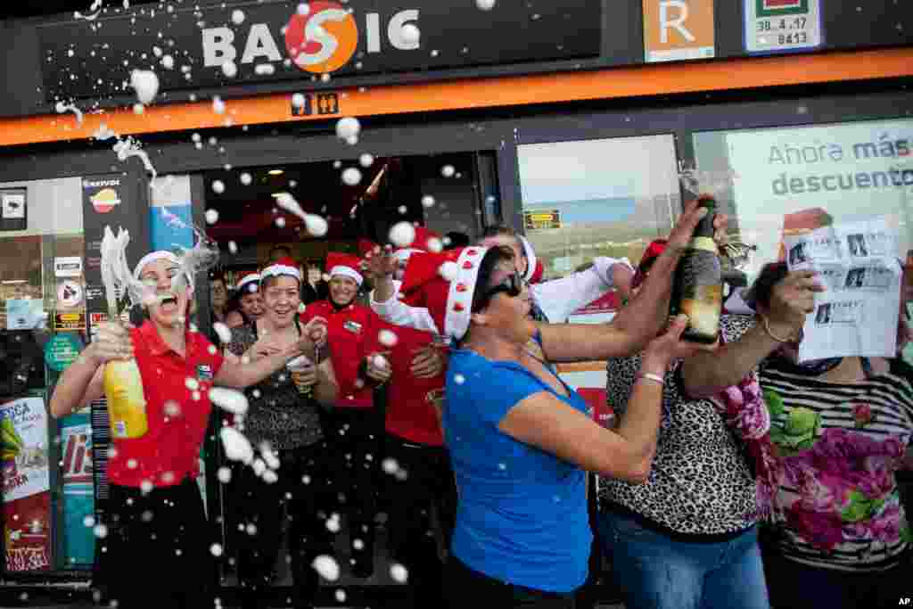 Para pekerja sebuah pom bensin bergembira bersama teman dan pelanggan setelah memenangkan lotere Natal “El Gordo” (“Si Gendut") di Santa Cruz de Tenerife di Kepulauan Canary, Spanyol (22/12). (AP/Andres Gutierrez)