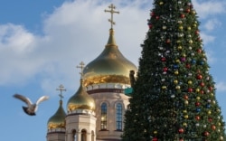 Seorang pekerja menghias pohon Tahun Baru untuk musim liburan mendatang di Vladivostok, Rusia, 12 Desember 2021. (Foto: Reuters)