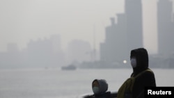 Orang-orang mengenakan masker pelindung dekat the Bund selama hari yang penuh polusi (19/1). Shanghai, China. (foto: REUTERS/Aly Song)