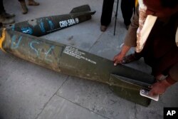 FILE - A Yemeni man displays an American-made CBU 58A/B, cluster bomb, in a police compound in Sanaa, Yemen, Oct. 5, 2016.