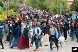 Migrants walk along a street after they arrived by train in Hegyeshalom, at the Austrian border, 169 km west of Budapest, Hungary, Oct. 7, 2015.