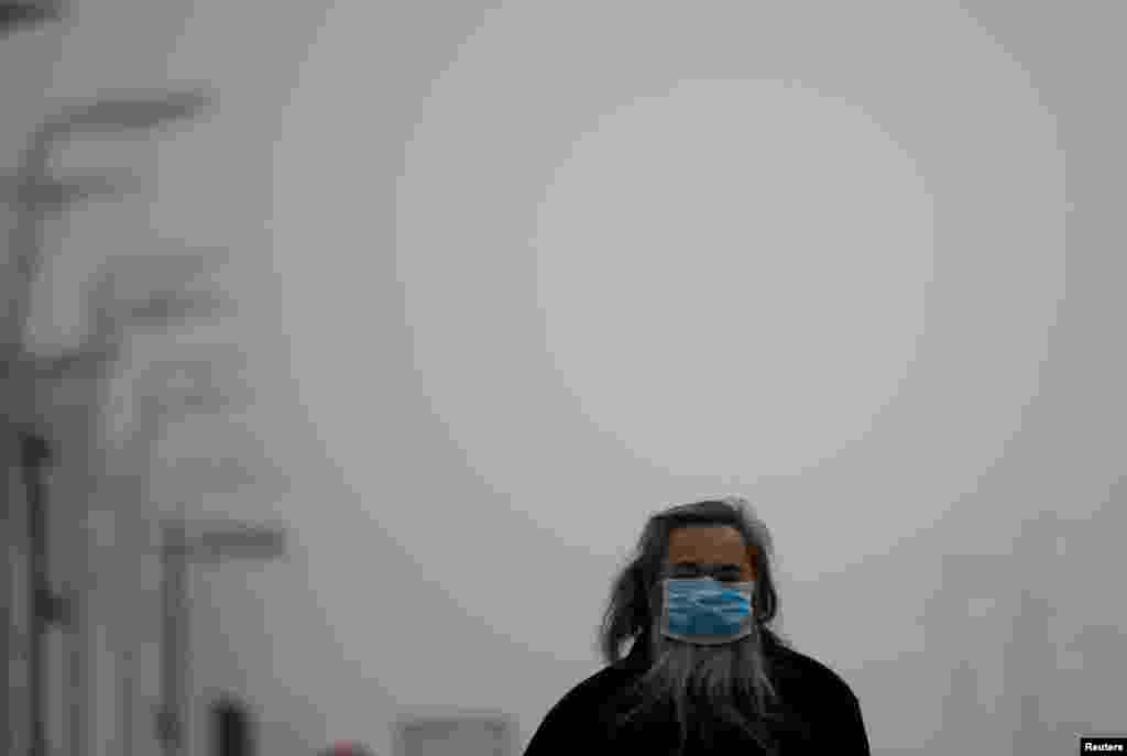 A man wearing a mask makes his way amid thick haze in Beijing, Feb. 25, 2014. 