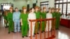 FILE - Doan Van Vuon, standing, fourth from left, and others stand with policemen in front of the dock at a court in Hai Phong, April 5, 2013, in this Vietnam News Agency photo.