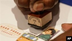 A postal service employee prepares to cancel the Rosa Parks' 100th birthday commemorative postage stamp at The Henry Ford museum in Dearborn, Mich., Monday, Feb. 4, 2013.