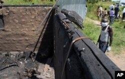 FILE - A man collecting bodies to bury in a mass grave approaches a burned hut containing charred corpses, on the outskirts of Yei, in southern South Sudan, Nov. 15, 2016.