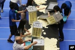 Election staff members open ballot boxes for vote counting in the upper house elections at a ballot counting center in Tokyo on July 10, 2016.