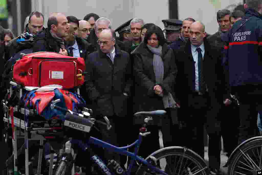 Le ministre de l'Intérieur français, Bernard Cazeneuve, centre gauche, et le maire de Paris Anne Hidalgo, centre-droit, arrivent au journal satirique bureau français de Charlie Hebdo, à Paris, le 7 janvier 2015.