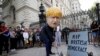  man in a giant Boris Johnson 'head' digs a grave at the foot of a pretend tombstone outside Downing Street in London, Wednesday, Aug. 28, 2019. 