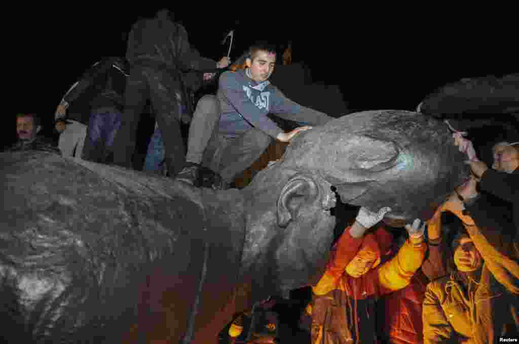 Demonstrators dismantle a statue of Vladimir Lenin during a pro-Ukraine rally in the central square of the eastern Ukrainian city of Kharkiv, Sept. 28, 2014.