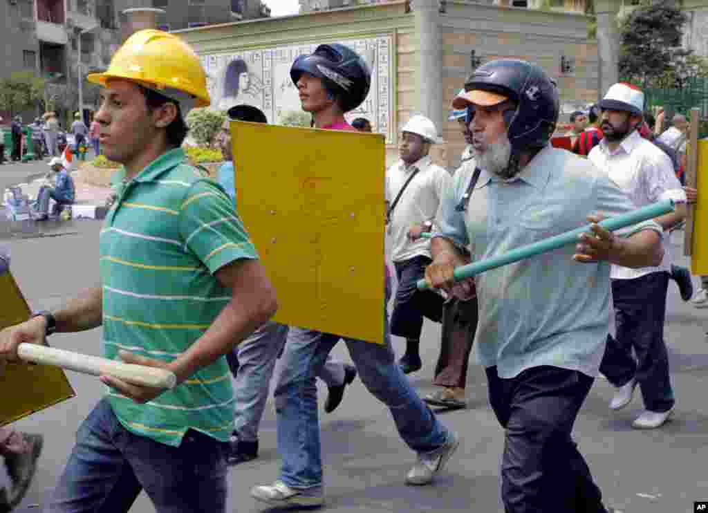 Sayed Saafan, 57, right, an Egyptian supporter of Egypt's Islamist President Mohammed Morsi, holds a stick and wears protective gear during training outside of the Rabia el-Adawiya mosque near the presidential palace, July 2, 2013.