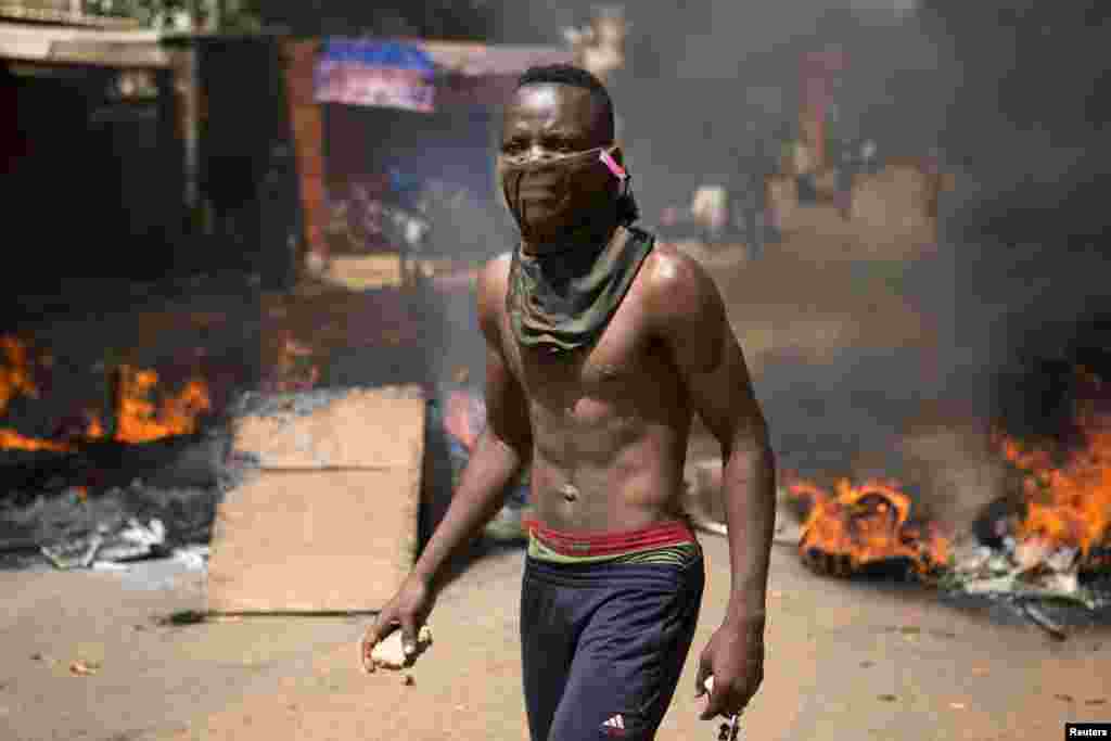 Un manifestant a des pierres dans ses mains sur une route barricadée à Ouagadougou, capitale de Burkina Faso, le 28 octobre 2014. La police a lancé des grenades à gaz lacrymogène aux manifestants qui ont usé des pierres à la fin d’une manifestation qui avait regroupé des dizaines de milliers de gens. REUTERS/Joe Penney