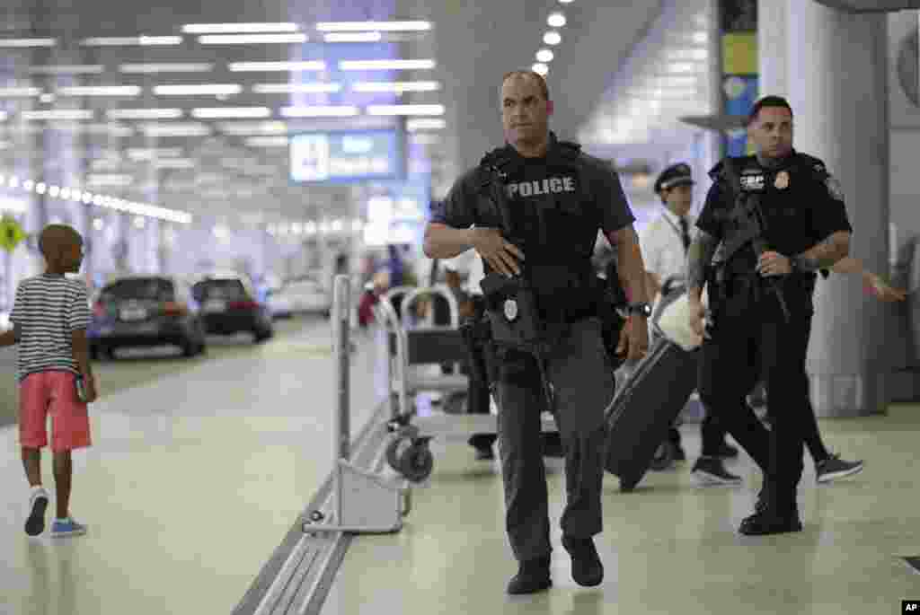 A Miami-Dade police officer, left, and a U.S. Customs and Border Protection officer, right, patrol outside of the departures area at Miami International Airport in Miami, Florida. There is increased security at the airport on this Independence Day holiday weekend after Tuesday's terrorist attacks at Istanbul's Ataturk International Airport.