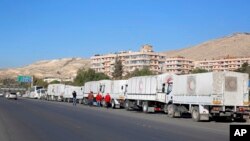 FILE - A convoy of humanitarian aid trucks waits before making its way into government-besieged towns in the Damascus countryside as part of a U.N.-sponsored aid operation, in Damascus, Syria, Feb. 17, 2016.
