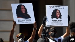 FILE - Signs are held up showing Breonna Taylor during a rally in her honor on the steps of the Kentucky State Capitol in Frankfort, Ky., June 25, 2020. 