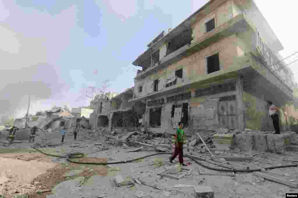 People inspect a site hit by what activists said was a barrel bomb dropped by forces loyal to Syria's President Bashar al-Assad in the al-Maadi neighborhood of Aleppo, June 20, 2014.