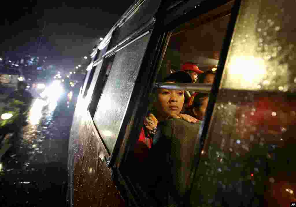 Para buruh Indonesia berlindung di dalam bus dari guyuran hujan ketika melakukan protes menuntut kenaikan upah di luar balai kota Jakarta.