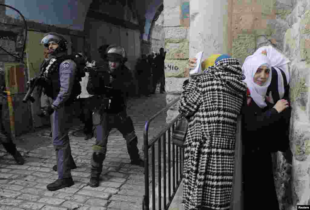 Palestinian women take cover as Israeli police use stun grenades to disperse a crowd trying to enter the compound known to Muslims as the Noble Sanctuary and to Jews as the Temple Mount in Jerusalem's Old City, Nov. 5, 2014.