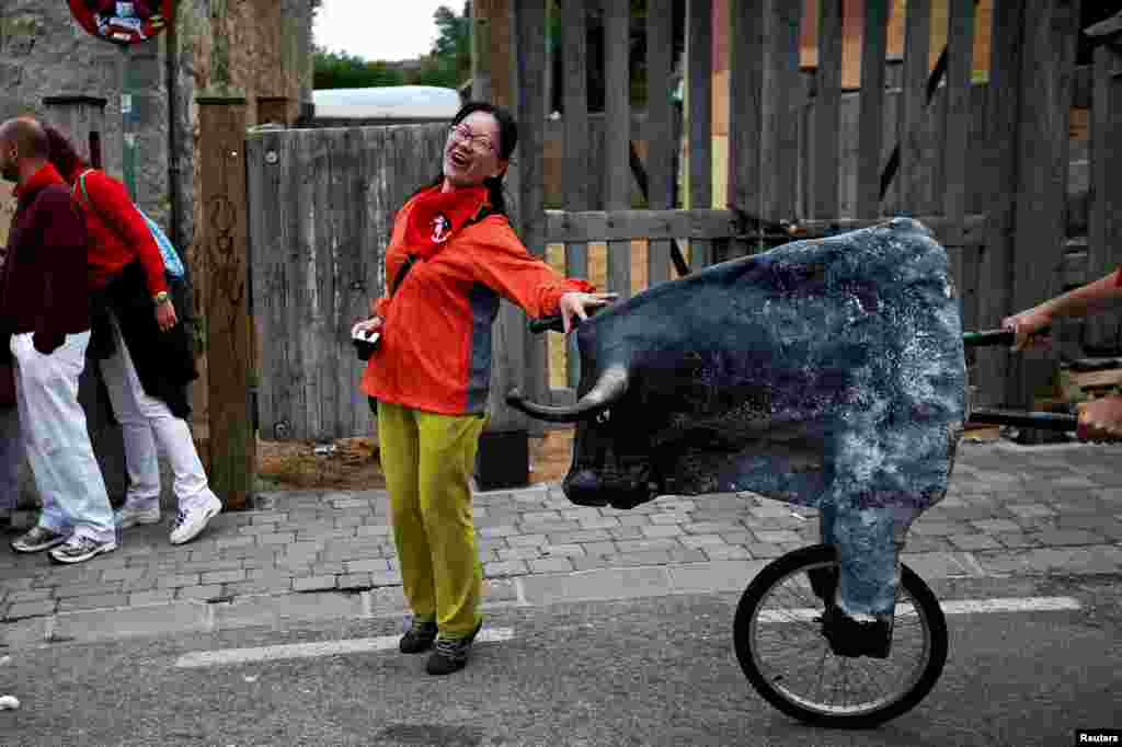 A woman is surprised by a toy bull during the Encierro Txiki (Little Bull Run) during the San Fermin festival in Pamplona, Spain.