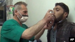 FILE - This video image from an anti-Bashar Assad activist group shows a Syrian being treated with an inhaler in Kfar Zeita, north of Damascus, after what witnesses said was a chlorine gas attack, April 18, 2014.