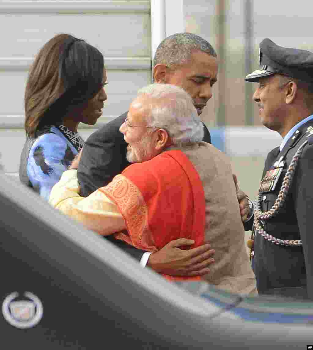Perdana Menteri India Narendra Modi dan Presiden AS Barack Obama berpelukan, sementara Michelle Obama terlihat bercakap-cakap dengan seorang pejabat di Pangkalan Angkatan Udara Palam di New Delihi (25/1).
