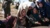 Relatives of Halil Yagmur, 64, who was killed Friday during mortar shelling from Syria, mourn over his grave at the cemetery in the town of Suruc, southeastern Turkey, at the border with Syria, Oct. 12, 2019. 