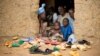 FILE - Refugees sit at the door of their home at the Minawao Refugee Camp in northern Cameroon.