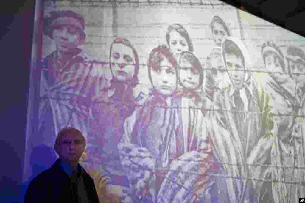 Penyintas Auschwitz-Birkenau Holocaust, Tomy Shacham, berpose sebelah foto yang menunjukkan dirinya, sebelah kiri, dalam upacara peringatan holocaust internasional di institut studi holocaust internasional Massuah (27/1) di Kibbutz Tel Yitzhak, Israel tengah. &nbsp;​(AP/Ariel Schalit)