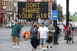 FILE - A sign encouraging the wearing of masks and keeping social distancing stands at a street corner in downtown Nashville, Tenn., Aug. 5, 2020.