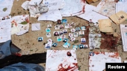 Des papiers d'identité nationaux tachés de sang et des photos d'électeurs devant un centre d'inscription des électeurs après un attentat-suicide à Kaboul, le 22 avril 2018.
