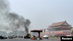 Asap mengepul tidak jauh dari foto besar Mao Zedong di Lapangan Tiananmen akibat sebuah jip menabrak kerumunan dan terbakar hari Senin (28/10). 