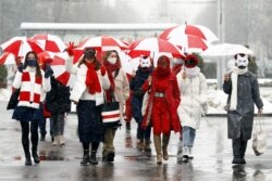Women wearing carnival masks march carrying umbrellas with the colors of the former white-red-white flag of Belarus to protest against the August 9, 2020, presidential election results in Minsk, Belarus on January 26, 2021.