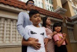 Journalist Yeang Sothearin stands with his family in front of the municipal court, in Phnom Penh, Cambodia, Oct. 3, 2019.