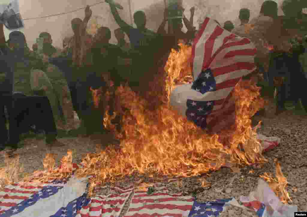 Supporters of Shi'ite cleric Moqtada al-Sadr burn a banner representing the U.S. flag during a protest in Baghdad's Sadr City,July 3, 2009.