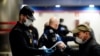 Polisi Spanyol membagikan masker di sebuah stasiun kereta metro di Madrid, Senin (13/4). 
