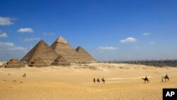 FILE - In this April 9, 2015 image tourists ride camels at the historical site of the Giza Pyramids in Giza, near Cairo, Egypt. Republican presidential candidate Ben Carson says it’s still his belief the great pyramids Egypt were built by the Biblical figure Joseph to store grain, and not as tombs for pharaohs.