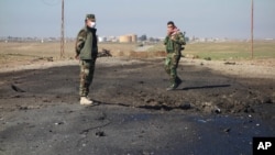 Dua tentara Kurdi Irak menyelidiki lokasi serangan bom oleh ISIS yang diduga berasal dari senjata kimia di Irak utara (14/3).