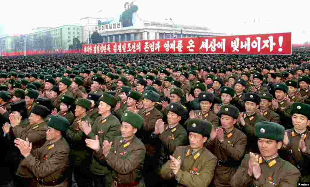 Warga Korea Utara merayakan keberhasilan peluncuran roket Unha-3 di alun-alun Kim Il Sung square di Pyongyang pada 14 Desember 2012. Tulisan yang tertera pada spanduk berarti "Mari muliakan martabat dan kehormatan pemimpin besar Kim Il Sung dan Kim Jong Il di dunia!".