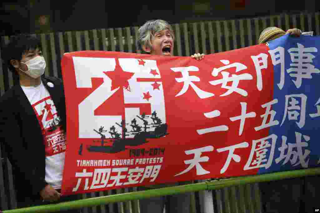 Seorang demonstran membentangkan spanduk sementara beberapa demonstran lainnya meneriakkan slogan di depan Kedubes China di Tokyo, Jepang (4/6).