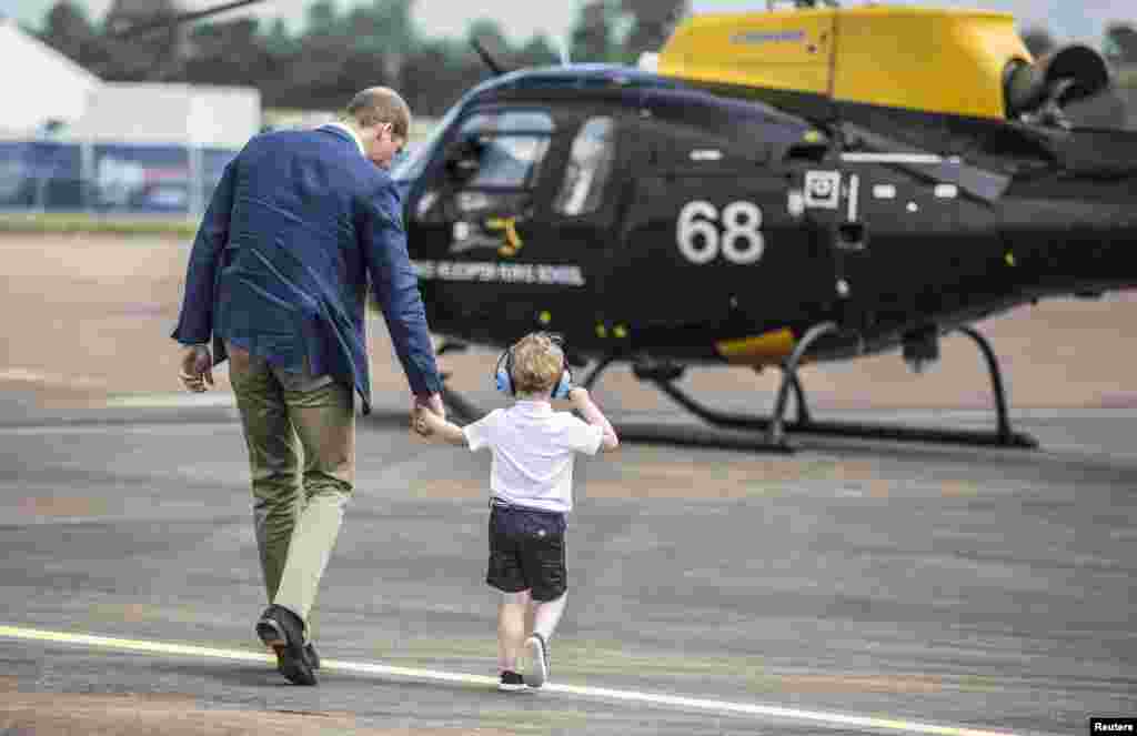Britain's Prince George walks with his father Prince William during a visit to the Royal international air show at RAF Fairford.