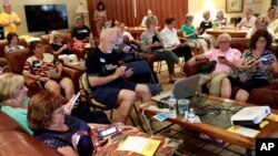 FILE - Community activists learn how to register voters on their phones at a democratic Stand Indivisible AZ monthly meeting in Scottsdale, Ariz., as they strategize about upcoming midterm elections, July 16, 2018.