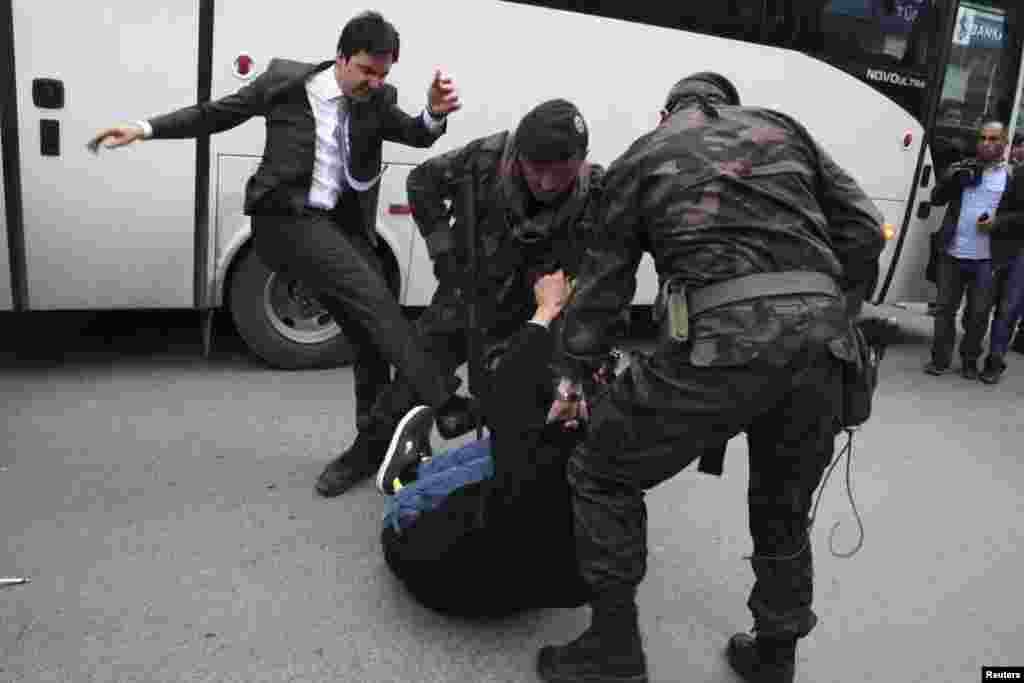 A protester is kicked by Yusuf Yerkel, advisor to Turkey's Prime Minister Tayyip Erdogan, as Special Forces police officers detain him during a protest against Mr. Erdogan's visit to Soma, May 14, 2014.