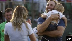 Dustin Johnson, right, greets his fiancée Paulina Gretzky as he holds their son Tatum Gretzky on the 18th hole during the final round of the U.S. Open golf championship at Oakmont Country Club on Sunday, June 19, 2016.