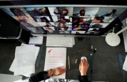 FILE - A student takes classes online with his companions using the Zoom app at home.