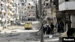 Free Syrian Army fighters walk along a street piled with damaged building as they head toward the frontline in Aleppo's Salaheddine district, April 8, 2013.
