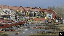 An employee of Henryville High School in Henryville, Indiana, examines the remains of the building following severe storms and tornadoes, March 2, 2012.